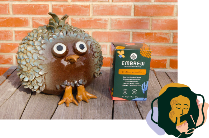 a bird sculpture on a table with a variety box of embrew tea